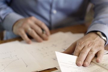 Hands of a businessman making calculations on a paper sheet. Soft background