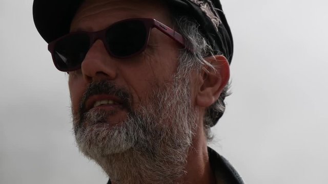 Uomo espressivo con barba occhiali e cappello