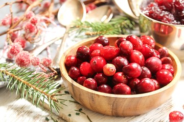 Raw Cranberries served in a wooden bowl  on white wooden background, selective focus