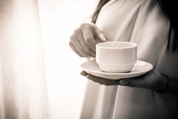 beautiful happiness caucasian girl enjoy morning moment with hot coffee in white tshirt with light from white curtain