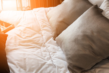 Bed maid-up with clean white pillows and bed sheets in beauty room. Close-up. Lens flair in sunlight.