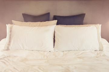 Bed maid-up with clean white pillows and bed sheets in beauty room. Close-up. Lens flair in sunlight.