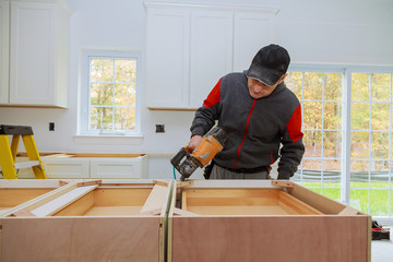 Young female carpenter using a nail gun while working in a workshop