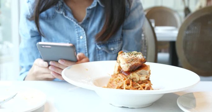 Woman take photo with cellphone on spaghetti dish
