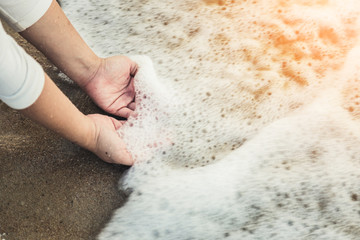 Hands holding a ocean soft wave on beach sand texture holiday cocnept
