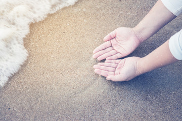 Hands holding a ocean soft wave on beach sand texture holiday cocnept