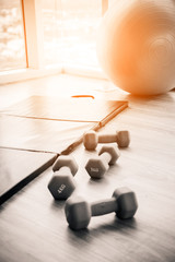 healthy concept with fitness center dumbell rack and yoga ball with exercise mat on wooden floor with background of blue sky