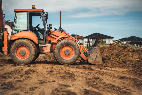 Industrial Machinery At Construction Site. Close Up Of Backhoe Loader Working