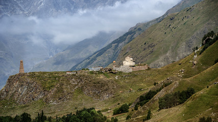 Georgia. An ancient church and a watchtower in the background of the mountains near the Georgian Military Road in the Gudauri district.