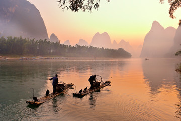 Silhouette of Two Fishing Men and His Cormorants on Li River at Sunrise, Guilin, China. The Li River or Lijiang is a river in Guangxi Zhuang Autonomous Region, China.