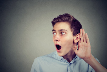 Amazed young man eavesdropping listening to latest rumor