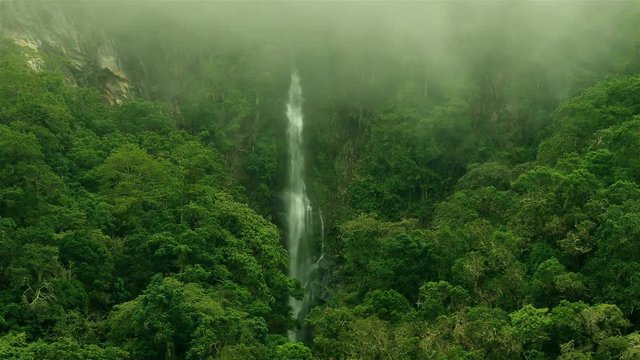 Epic waterfall Nature background full hd and 4k. High Humidity In Jungle Rainforest with a powerful waterfall. Timelapse Of Moving Clouds And Fog over a waterfall between Green mountains. Ecology. 
