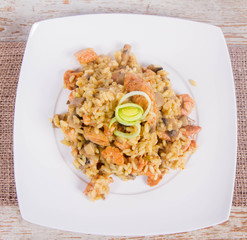 Risotto with mushrooms and chicken decorated with leek on a wooden background