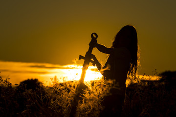 Boy pulling up a sword with the setting sun in the background - 180277739