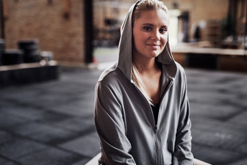 Obraz premium Smiling young woman wearing exercise clothing sitting in a gym