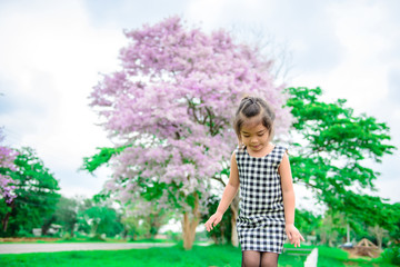 Obraz na płótnie Canvas Portrait of cute little girl on beautiful flowers on tree background,colorful tone