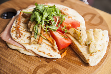 Sandwich with ham, tomato, cheese and golden French fries potatoes on a wooden plate