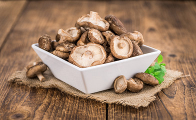 Portion of Raw Shiitake mushrooms on wooden background, selective focus