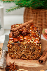 Homemade holiday Fruitcake with nuts, fruits and spices. Almonds, cinnamon, star anise, cardamom on the table. Traditional English pastries. Christmas. New year. Selective focus