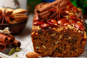 Homemade holiday Fruitcake with nuts, fruits and spices. Almonds, cinnamon, star anise, cardamom on the table. Traditional English pastries. Christmas. New year. Selective focus