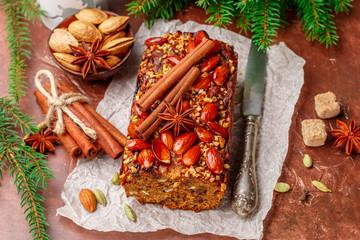 Homemade holiday Fruitcake with nuts, fruits and spices. Almonds, cinnamon, star anise, cardamom on the table. Traditional English pastries. Christmas. New year. Selective focus
