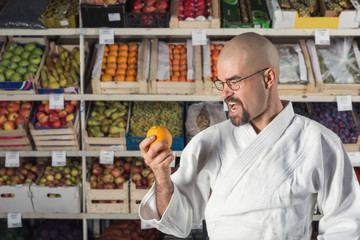 A man against the background with racks with fruits and vegetables dressed in Japanese kimono and hakama. Fruitarianism concept