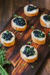 Appetizer for christmas table - black caviar on the pieces of bread.