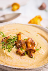 Chanterelle mushroom cream soup with thyme and garlic on black background, closeup