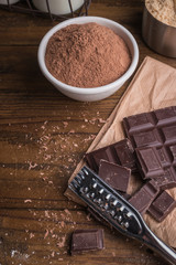 Dark chocolate and cocoa powder on rustic background and space for text