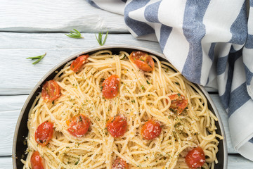 Spaghetti pasta with tomatoes and parsley on wooden table