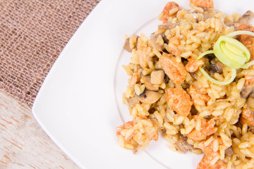Risotto with mushrooms and chicken decorated with leek on a wooden background