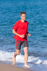 Fototapeta na wymiar Young man running on the beach in Costa Brava, Spain