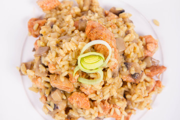 Risotto with mushrooms and chicken decorated with leek on a white background