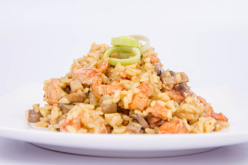 Risotto with mushrooms and chicken decorated with leek on a white background