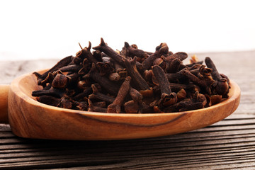 Many Dry cloves spice on brown wooden spoon.