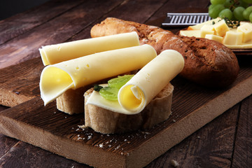 Cheese slices on bread or baghuette and grapes - obrazy, fototapety, plakaty