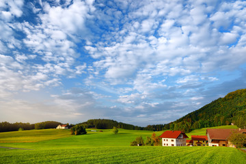 Breathtaking lansdcape of Austrian countryside on sunset. Dramatic sky over idyllic green fields of Anstrian Central Alps on autumn evening.