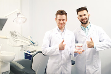 Two male dentists showing thumbs up