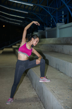 Asian slim girl stretching leg on stand night scene