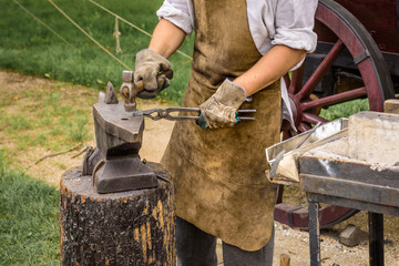 Blacksmith working on an iron object with a hammer during a workshop.