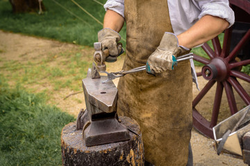Blacksmith working on an iron object with a hammer during a workshop.