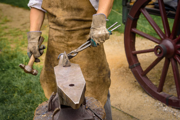 Blacksmith working on an iron object with a hammer during a workshop.