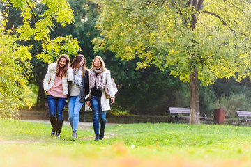 Obraz premium Three female friends walking in park