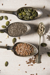 Food ingredients in old steel spoon on marble background. Flax, pumpkin seed, sunflower seed and sesame. healthy food concept