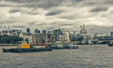 Dramatic view of London skyline at sunset. Cargo ships on Thames.