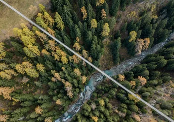 Fototapeten Aerial view of suspension bridge over narrow valley in Switzerland © Mario
