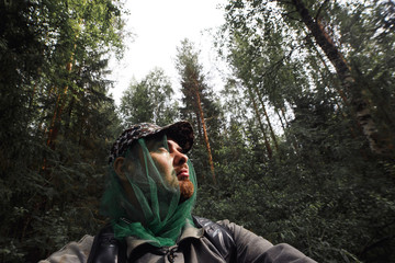 Man is walking in dense forest. Bearded traveler with backpack got lost