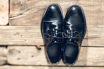 Classic black men's shoes on the wooden floor. Top view. Flat lay.