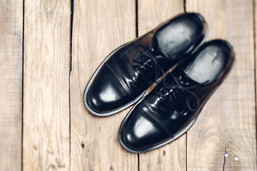 Classic black men's shoes on the wooden floor. Top view. Flat lay.