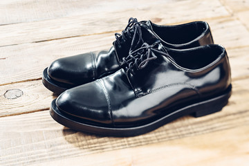 Modern lacquer men's shoes on the wooden floor.